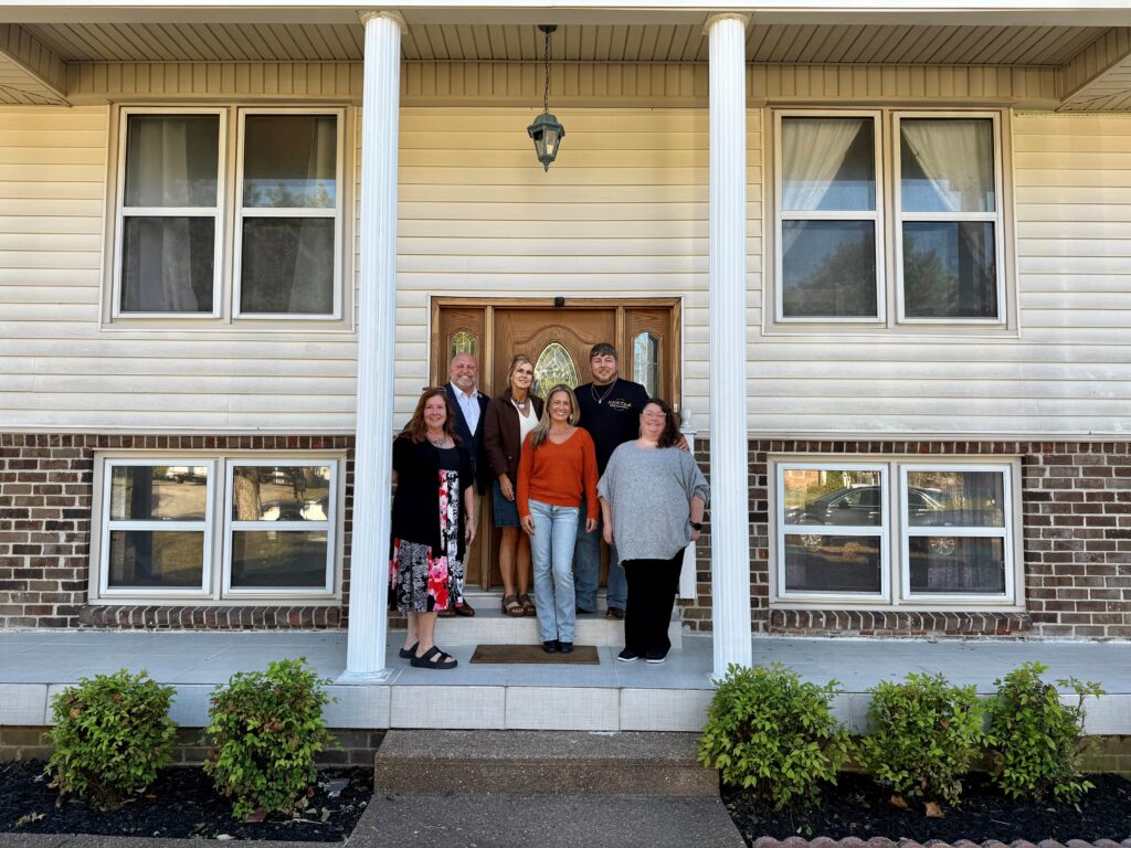 Team members standing on the front porch of a house with columns